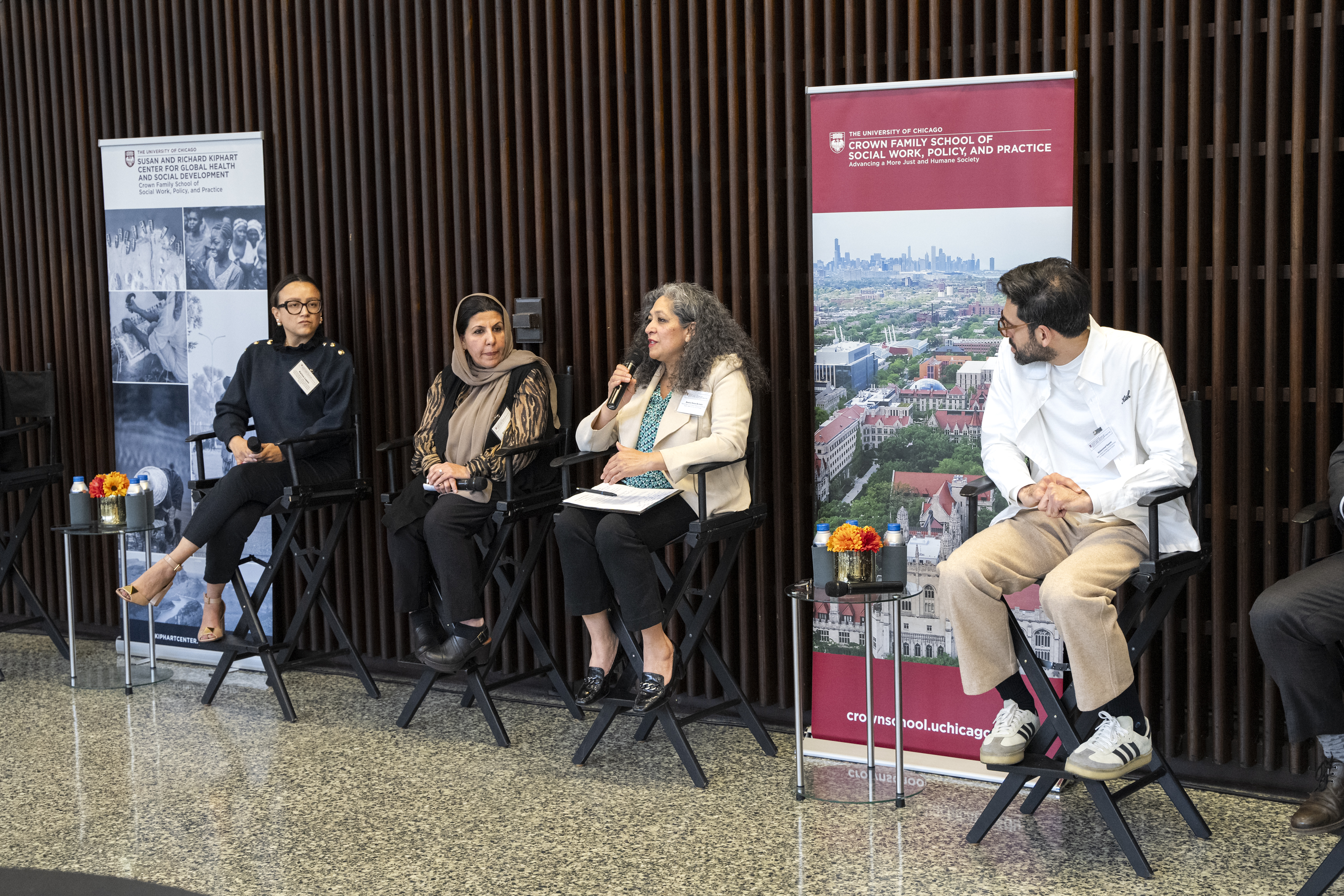 image of panel of people sitting in chairs while a woman holding a microphone speaks