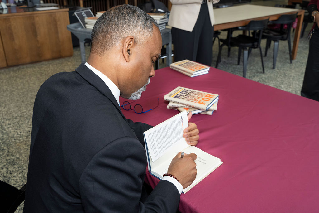 man sitting at table signing book