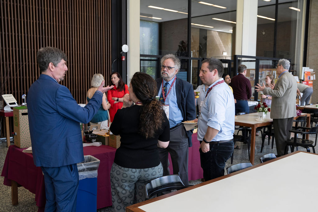 Group of people standing in different areas of the room talking 