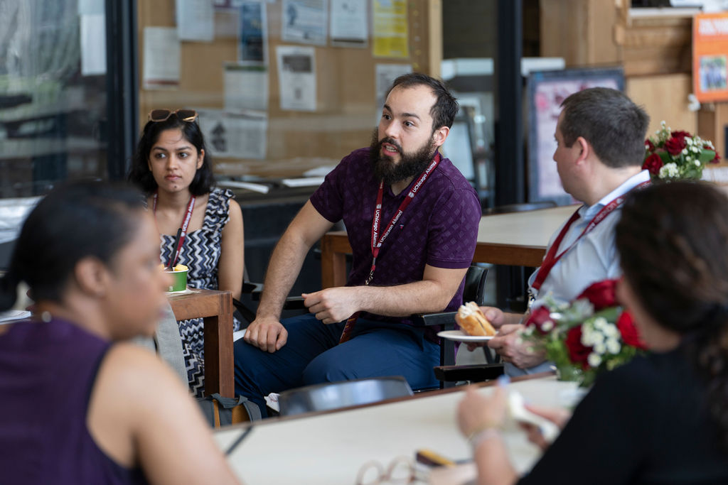 A man in a purple shirt waits turn to talk in a group discussion