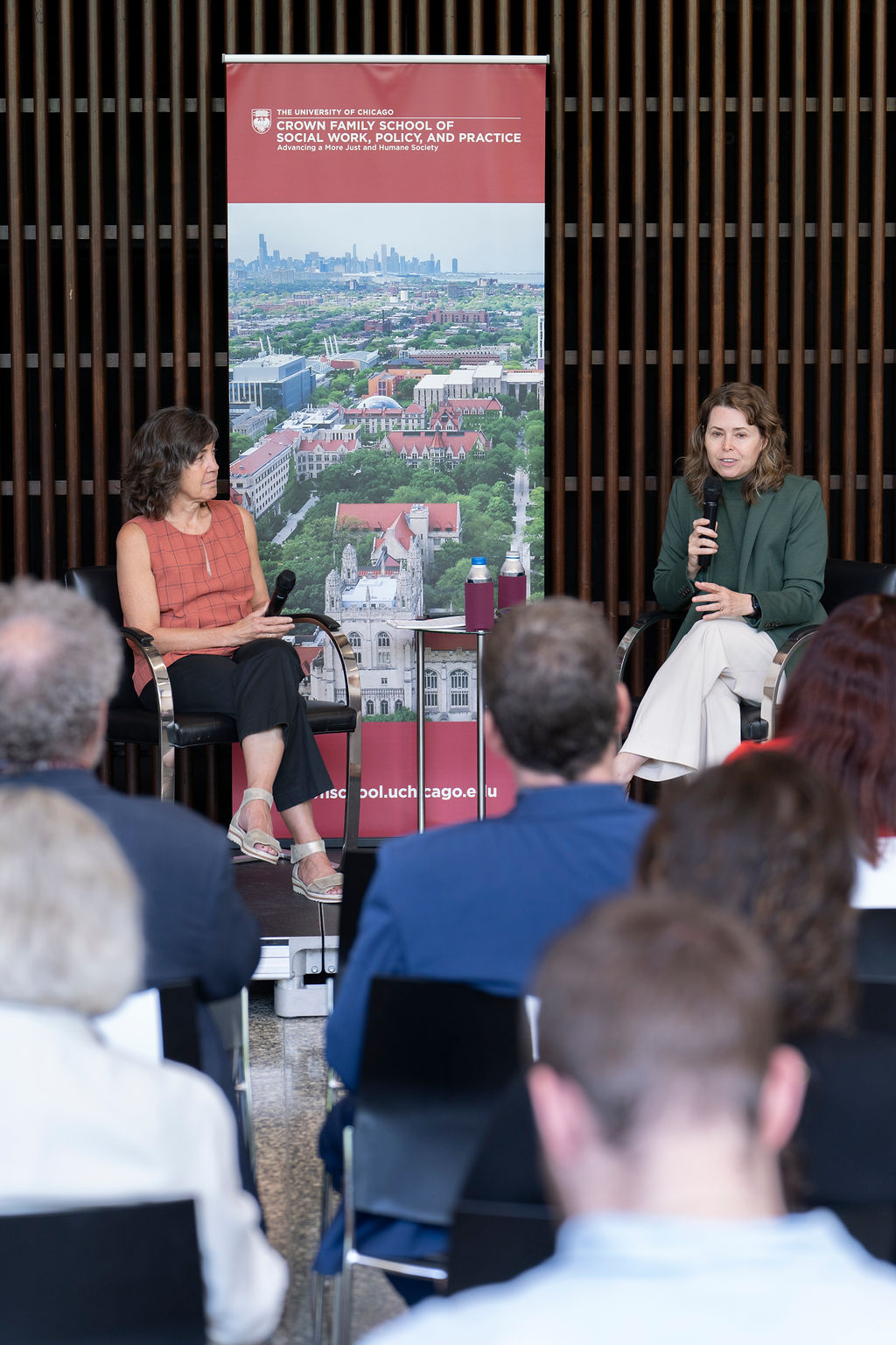 Two woman sit on stage in front of an audience having a discussion