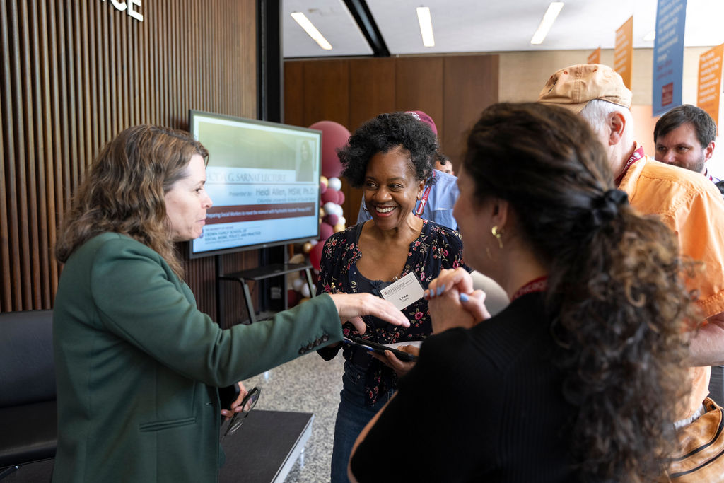 Woman in dark green blazer speak to two other women in small group