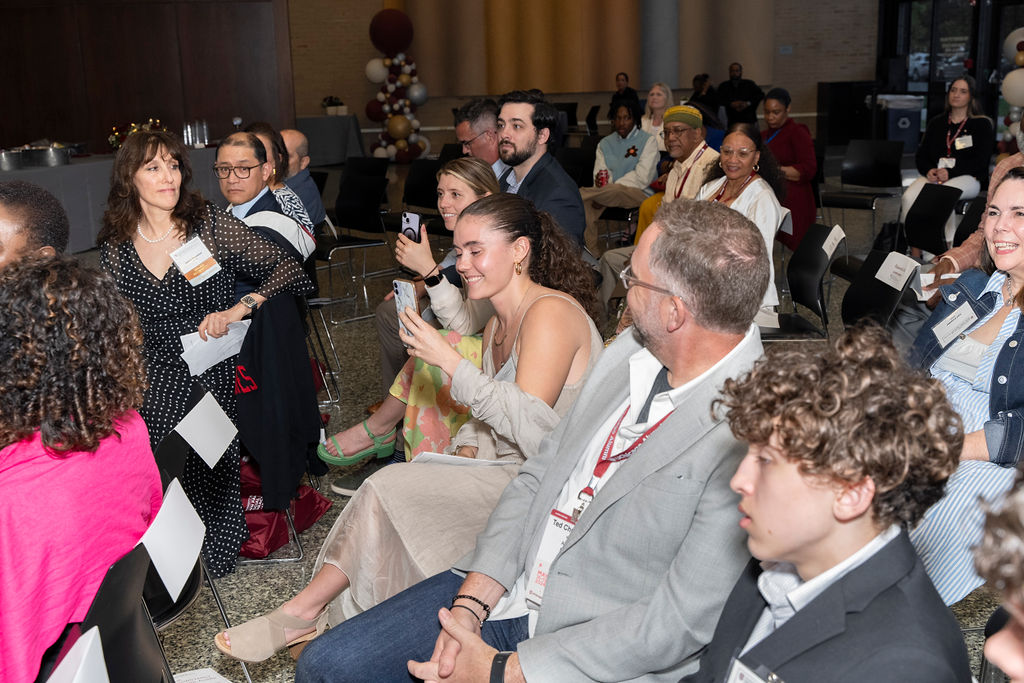 group of people at an event holding cellphones video a speaker