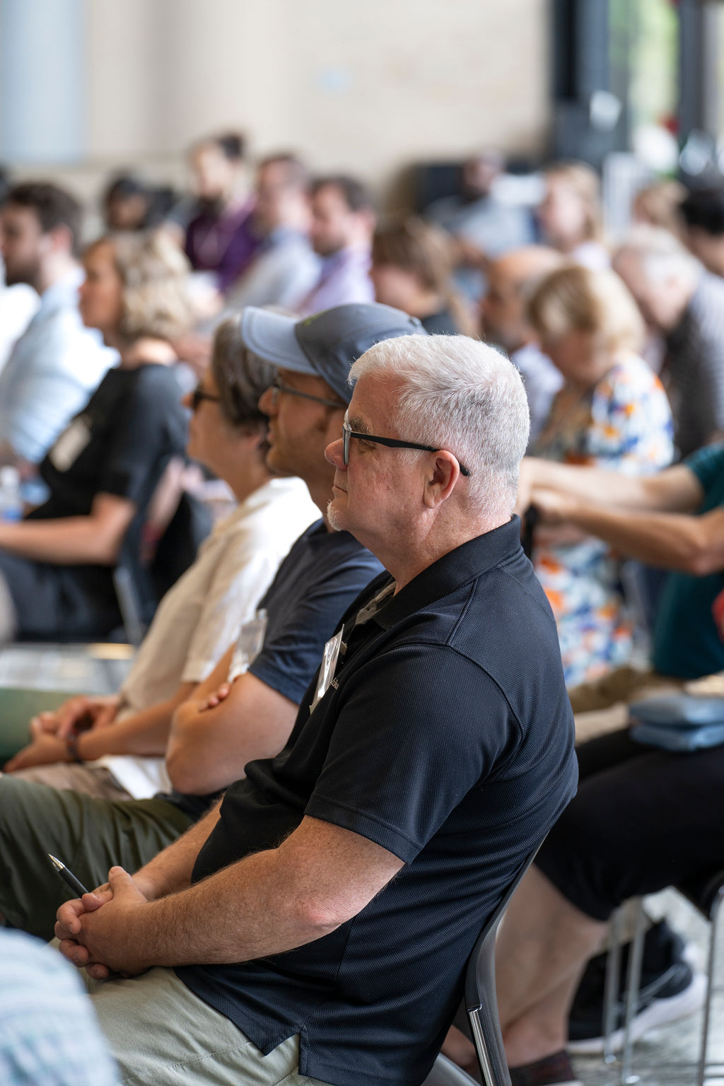 Man sitting in audience with dark shirt and glasses