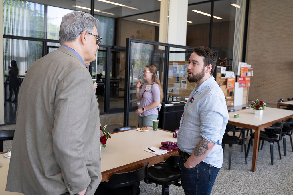 An alum and student talk in the library