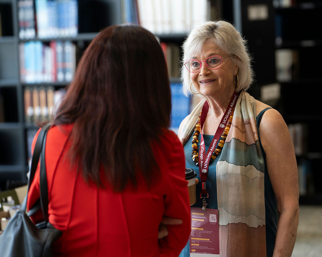 A woman has her back to the camera while another woman stands talking to her