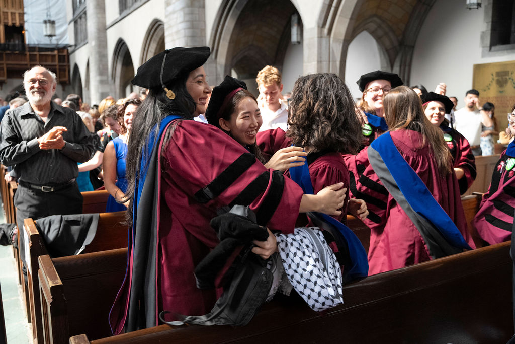 three graduates hug in excitement