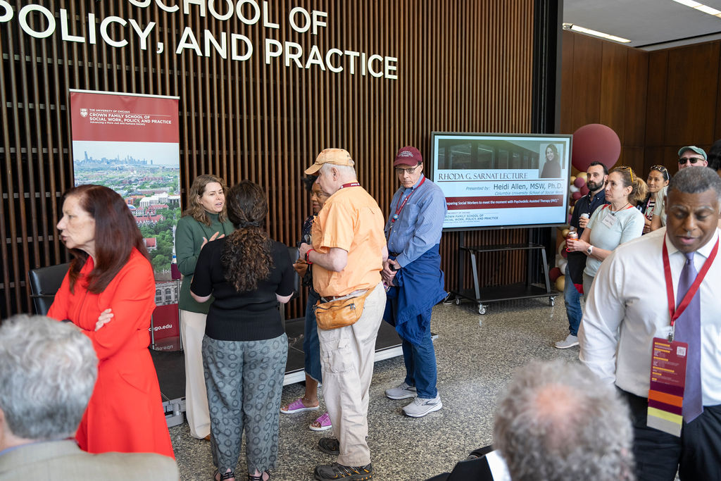 People stand around waiting to talk to the lecture speaker