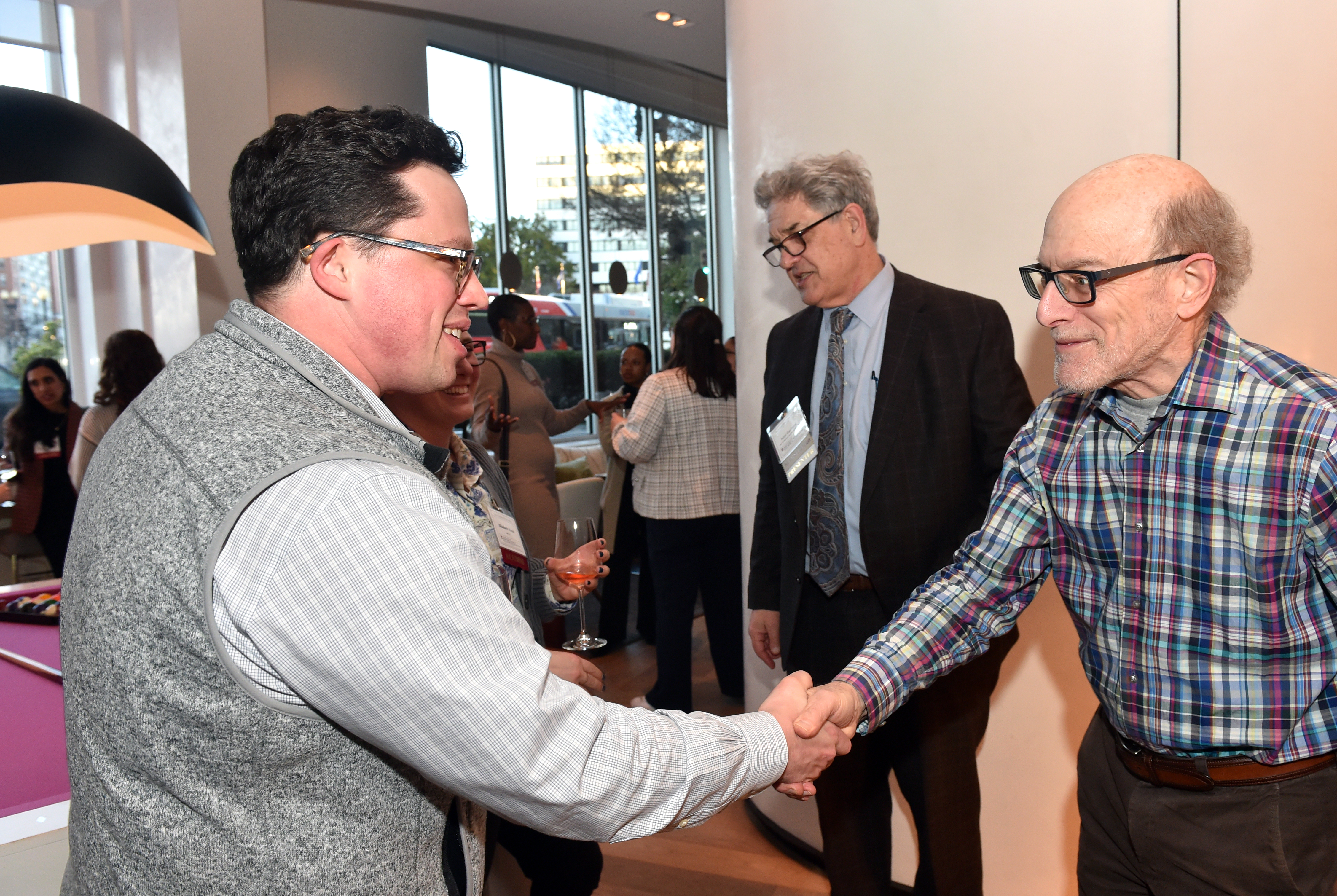 man in grey sweater shaking hands with man in checkered shirt