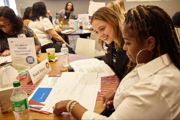 Two women looking at a booklet together collaborating