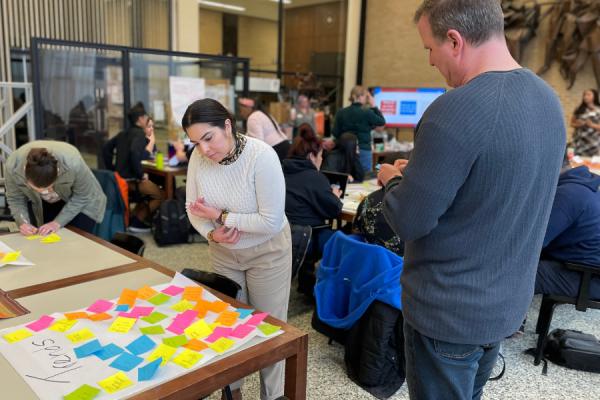 woman in a white sweater looking at a table with post it notes to add her thoughts to the collection