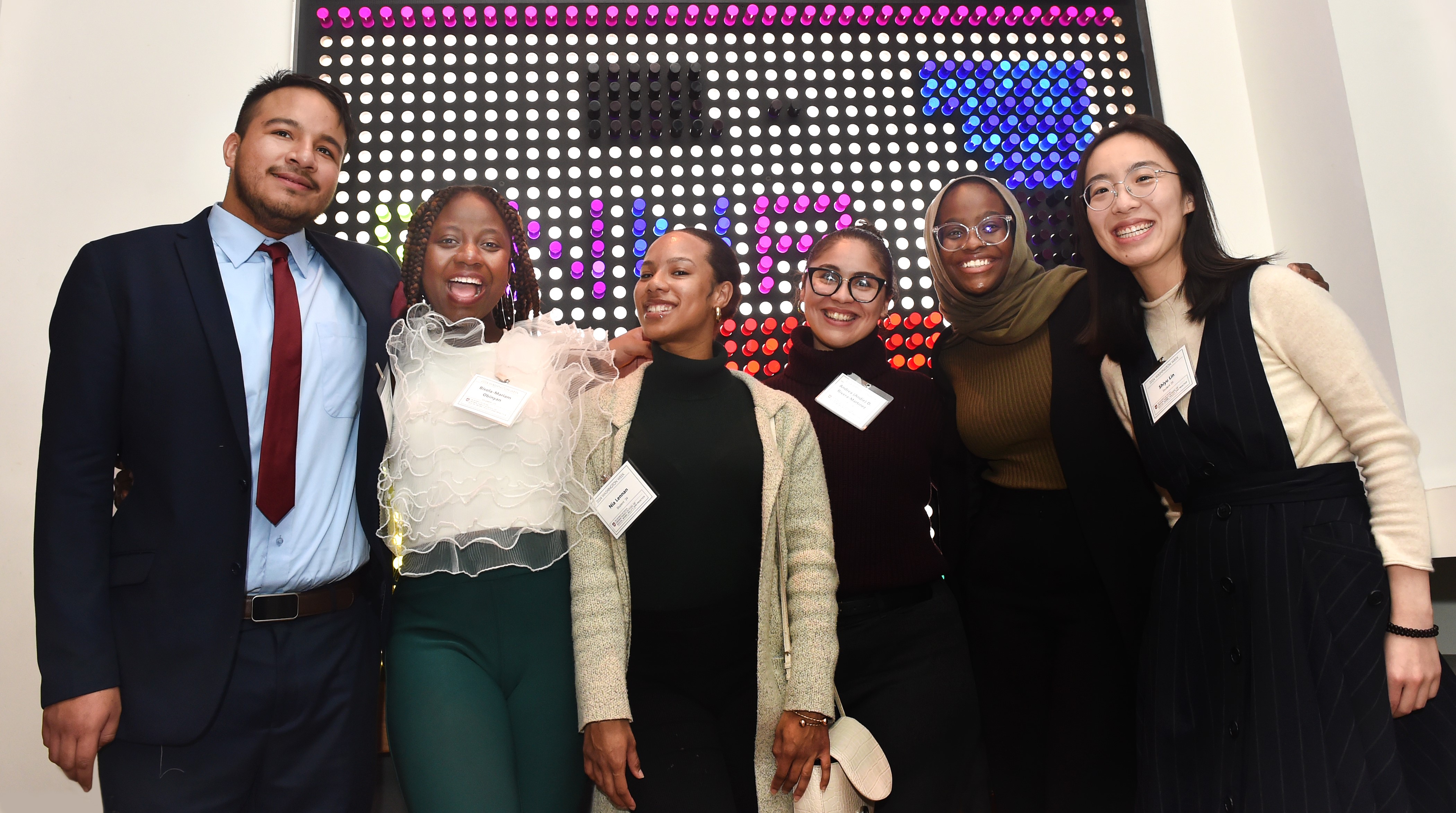 Group of students smiling in front of a lighted sign