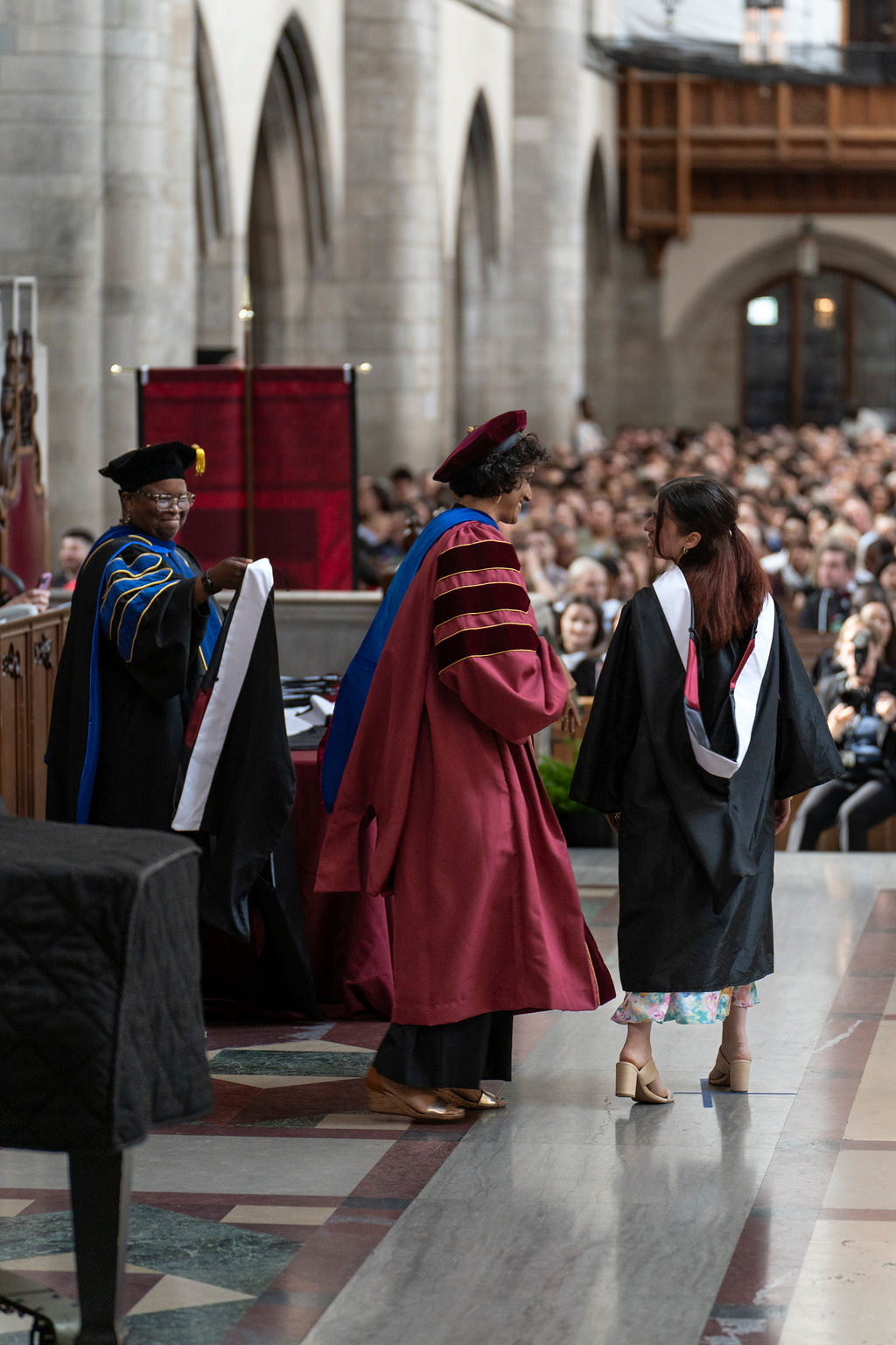 A graduate leaves the stage after receiving graduation regalia hood.