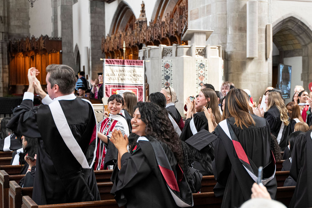 Graduates applaud as a group after receiving hoods.