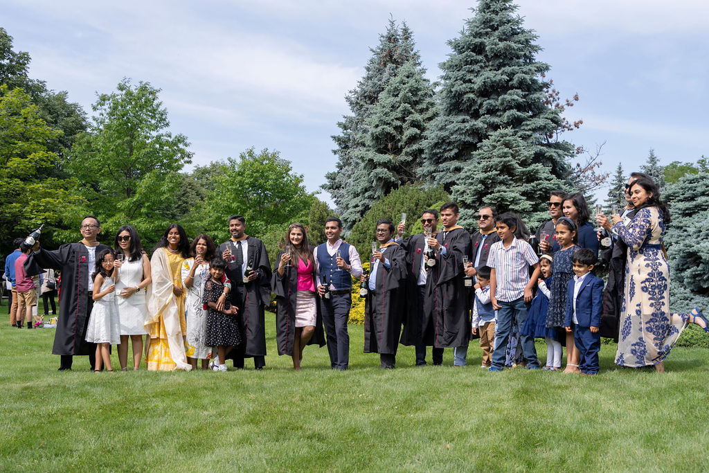 A family takes a group photo on the lawn following the hooding ceremony