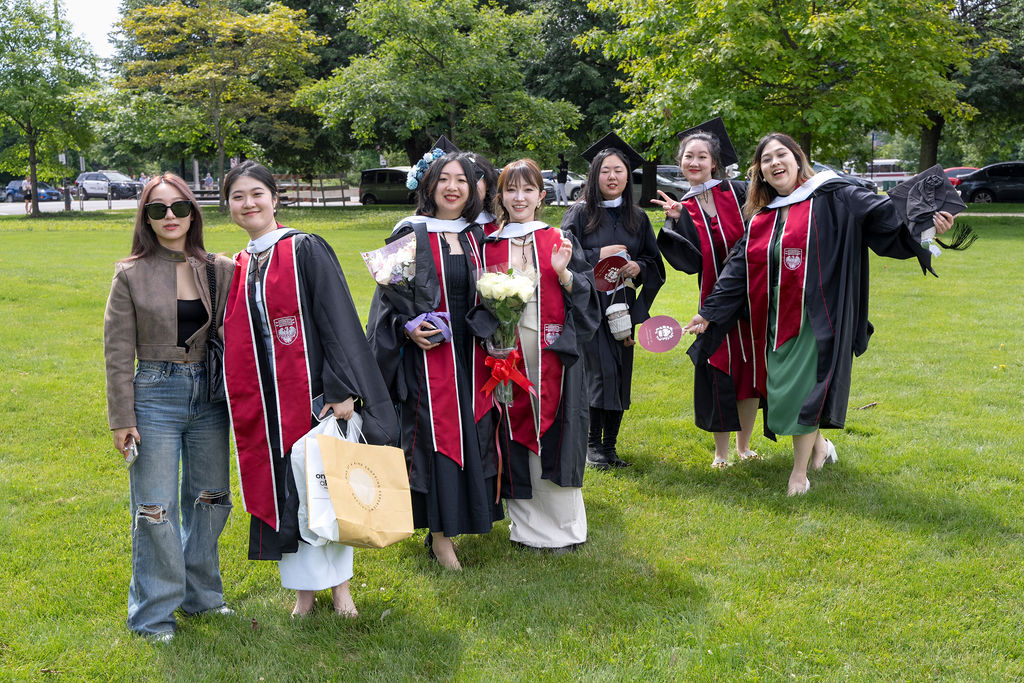 Graduates stand around on lawn to take photos with one another 