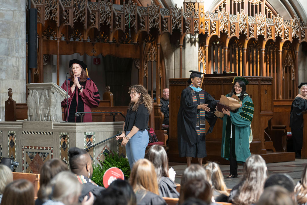 Dean Gorman Smith stands at podium at the start of the ceremony addressing audience and the graduates