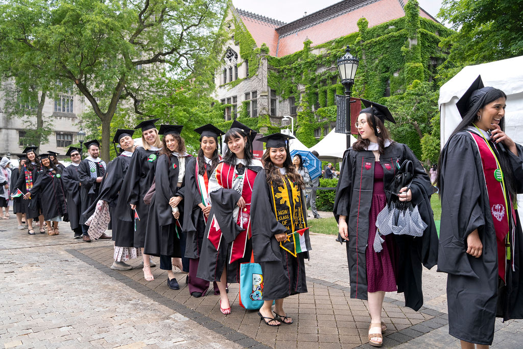 A group of graduates in academic regalia line up to enter the convocation ceremony