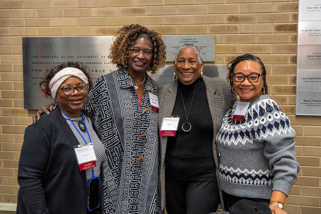 four women standing close togehter with all smling with name badges