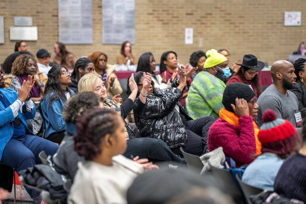 Group of people seated are clapping together.