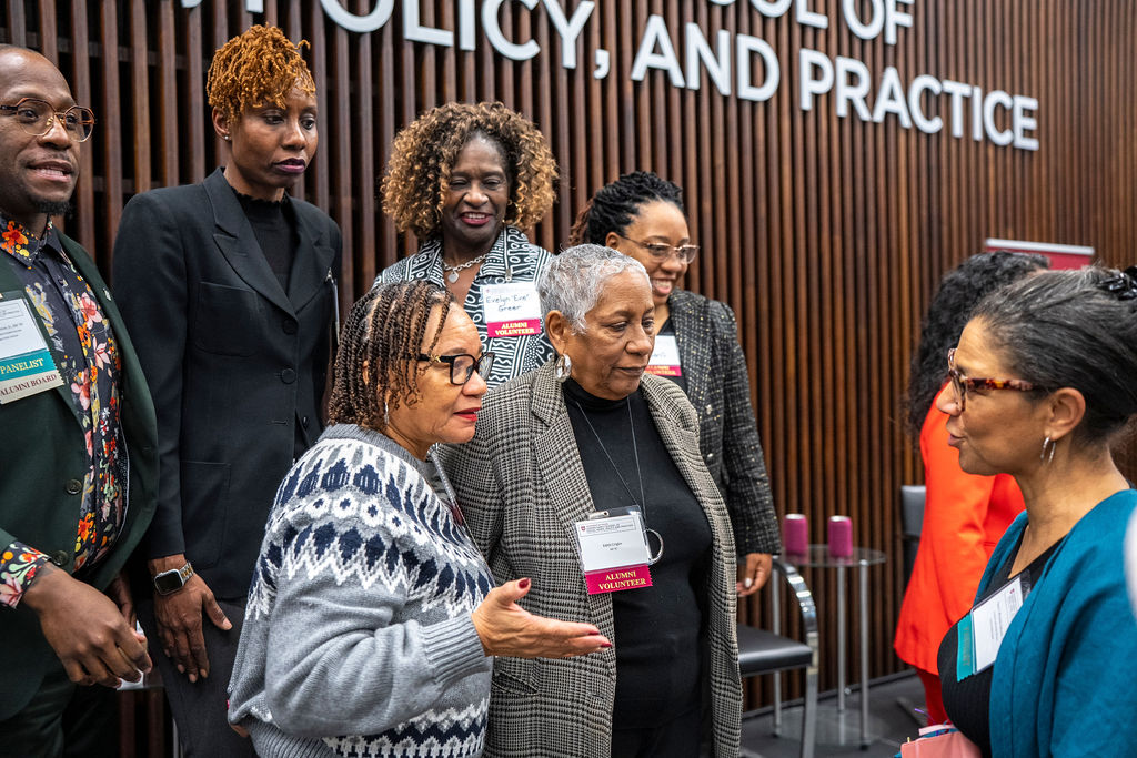 Group of people posing for a picture with a woman in grey talking to a person in blue cardigan