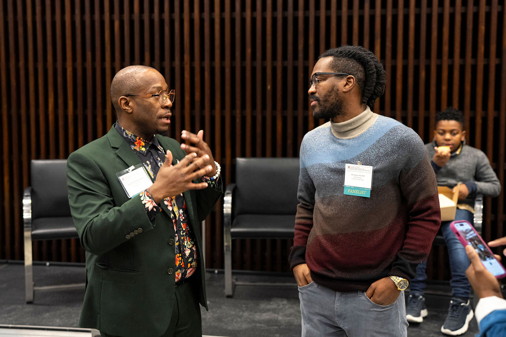 Two men wearing badges are speaking to each other 