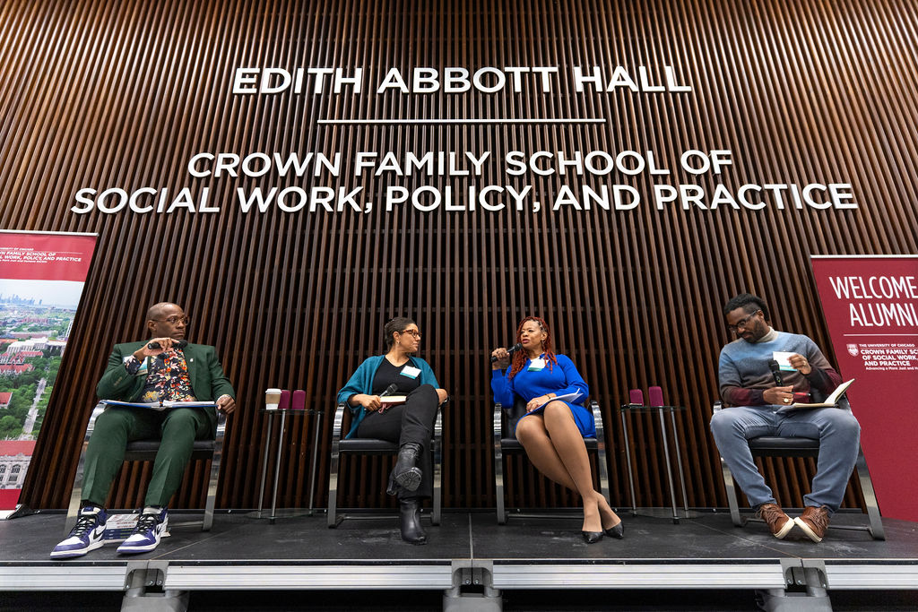Shot of the four panelists on stage in front of Edith Abbott Hall wall.