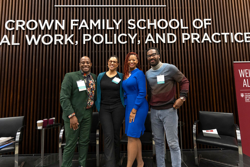 A group of people standing in front of a Social Work School sign with badges smiling