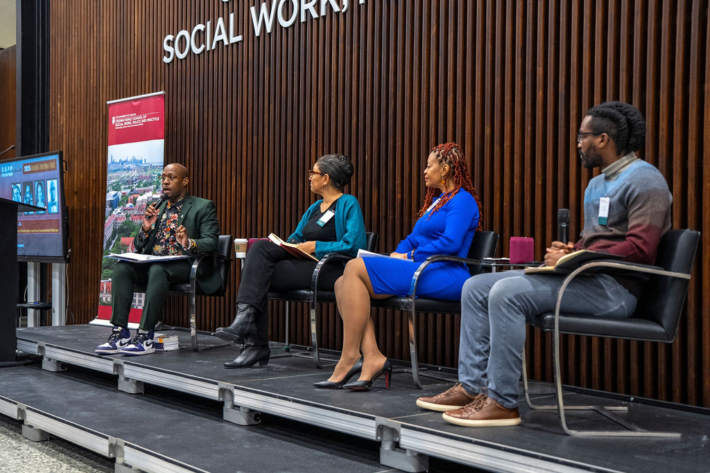 Four panelists sit on stage speaking to the audience 