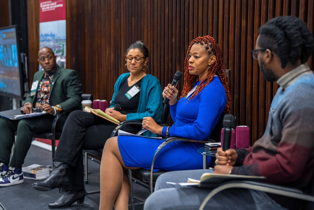 A black woman with red hair wearing wearing blue speaking into the microphone.