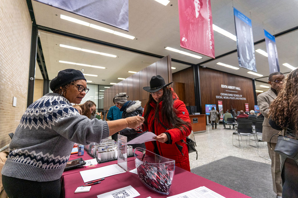 woman in grey sweater assisting a woman in a red jacket 