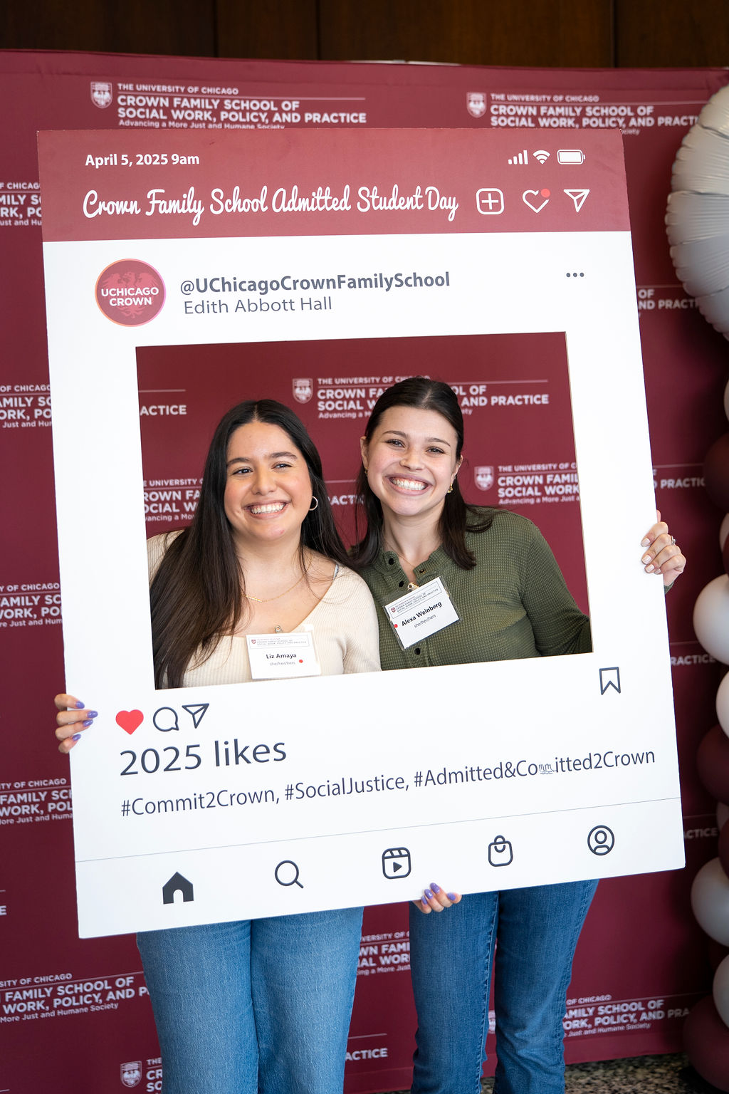 Woman with light cream long sleeve shirt posing with woman in green sweater with the social media photo prop, smiling widely.