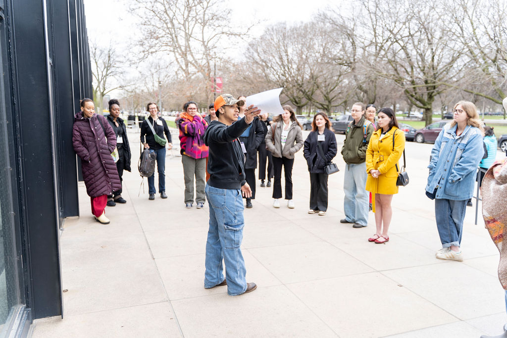 A group of students with a tour guide standing outside of the Crown School