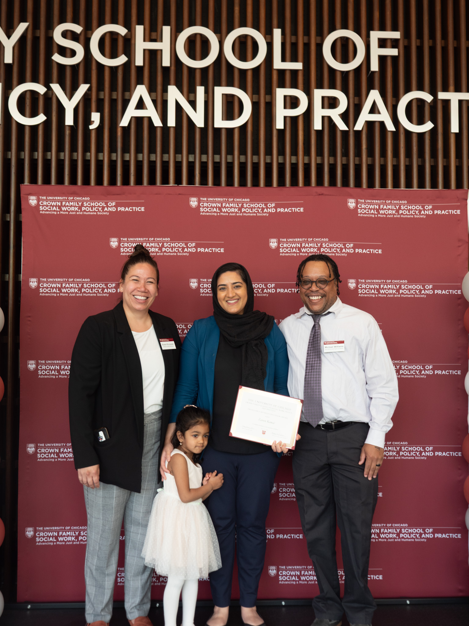 Student awardee taking picture with her family in front of backdrop