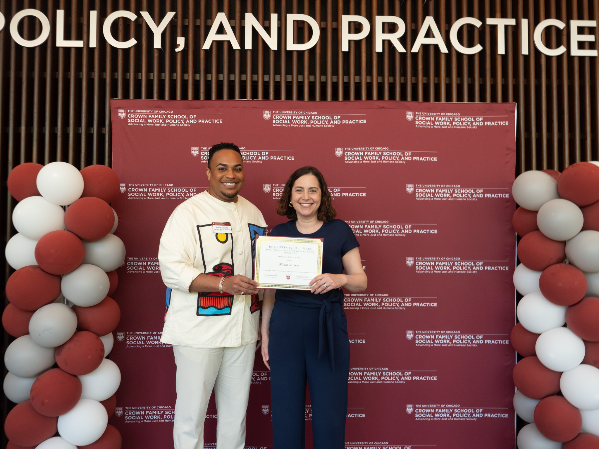 Student awardee taking picture with someone in front of backdrop