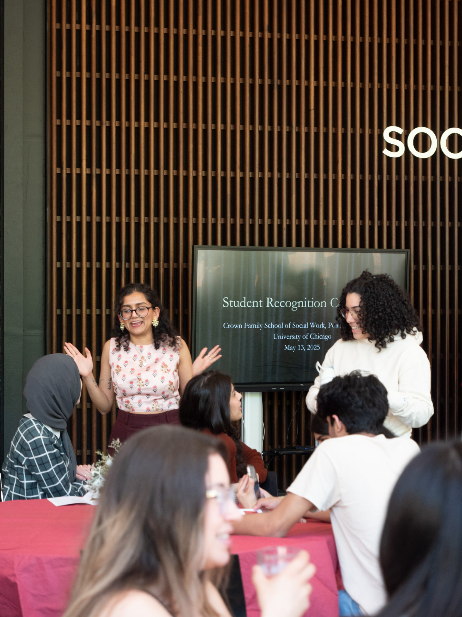 Women standing talking to women sitting at a table