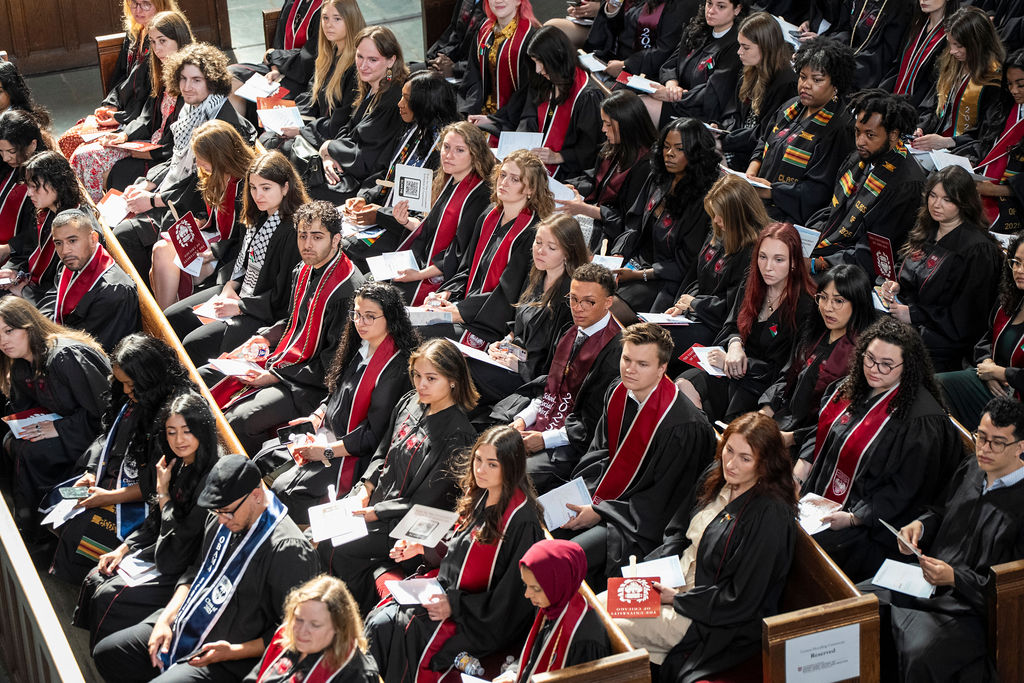 Group of graduates sitting in pews in regalia