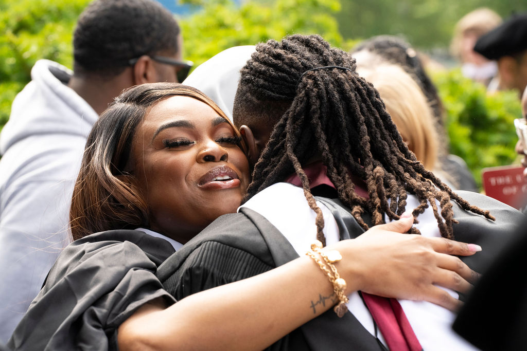 two graduates in regalia share a hug of celebration