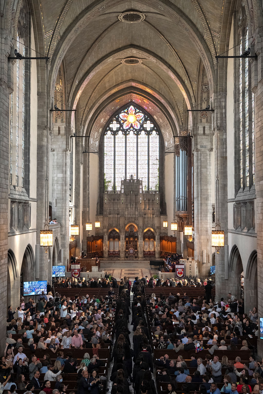 image of a grand chapel with a view of the backs of graduates as they process in