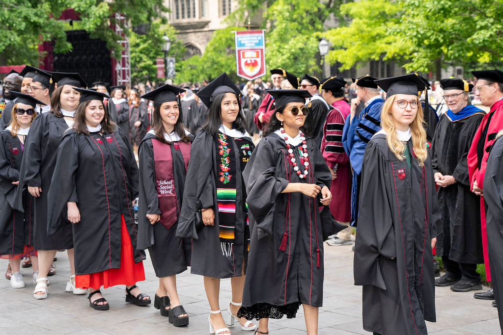 group of female graduates lined up all smiling with regalia and hats.