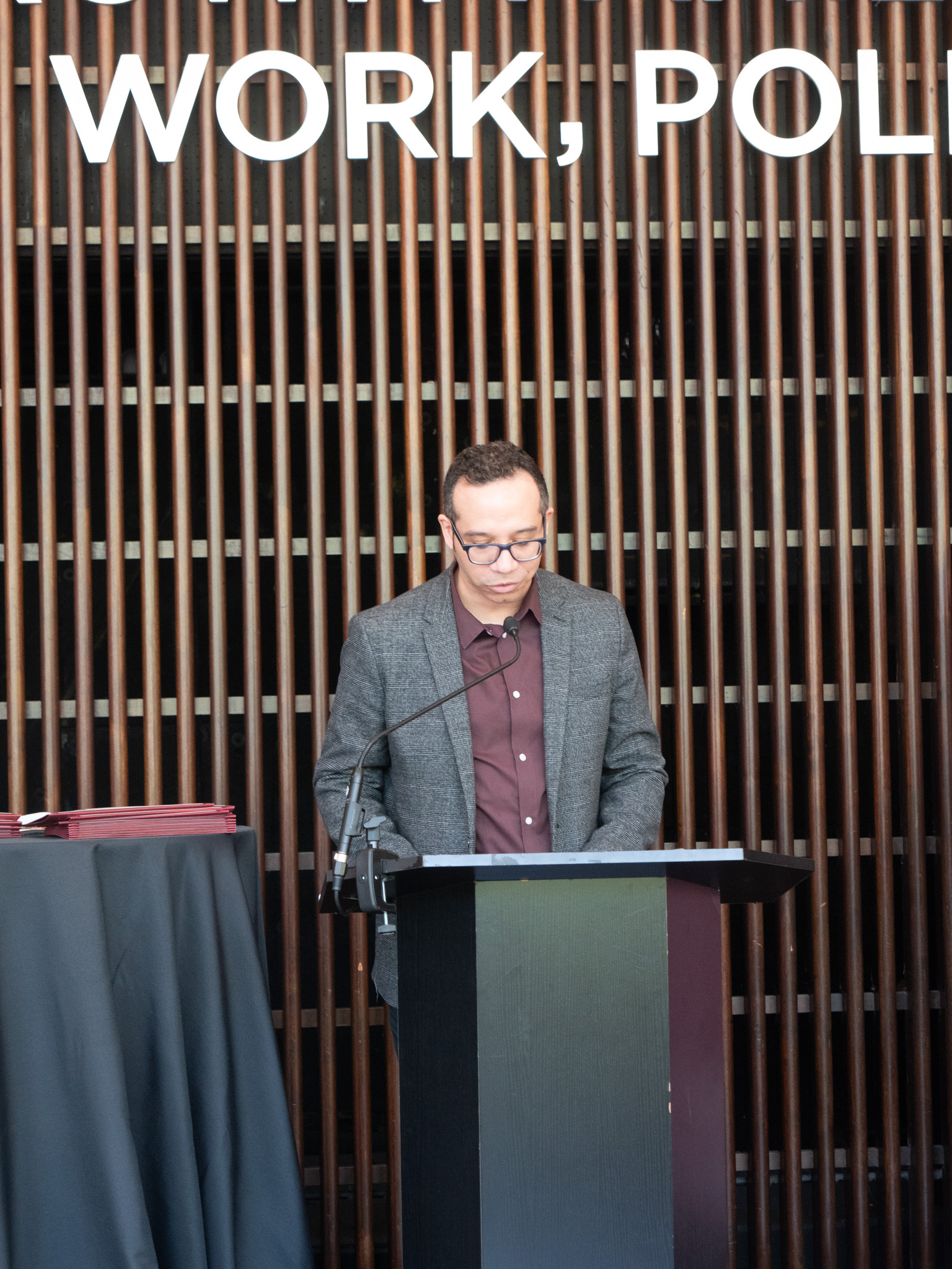 image of male in a grey suit at a podium speaking