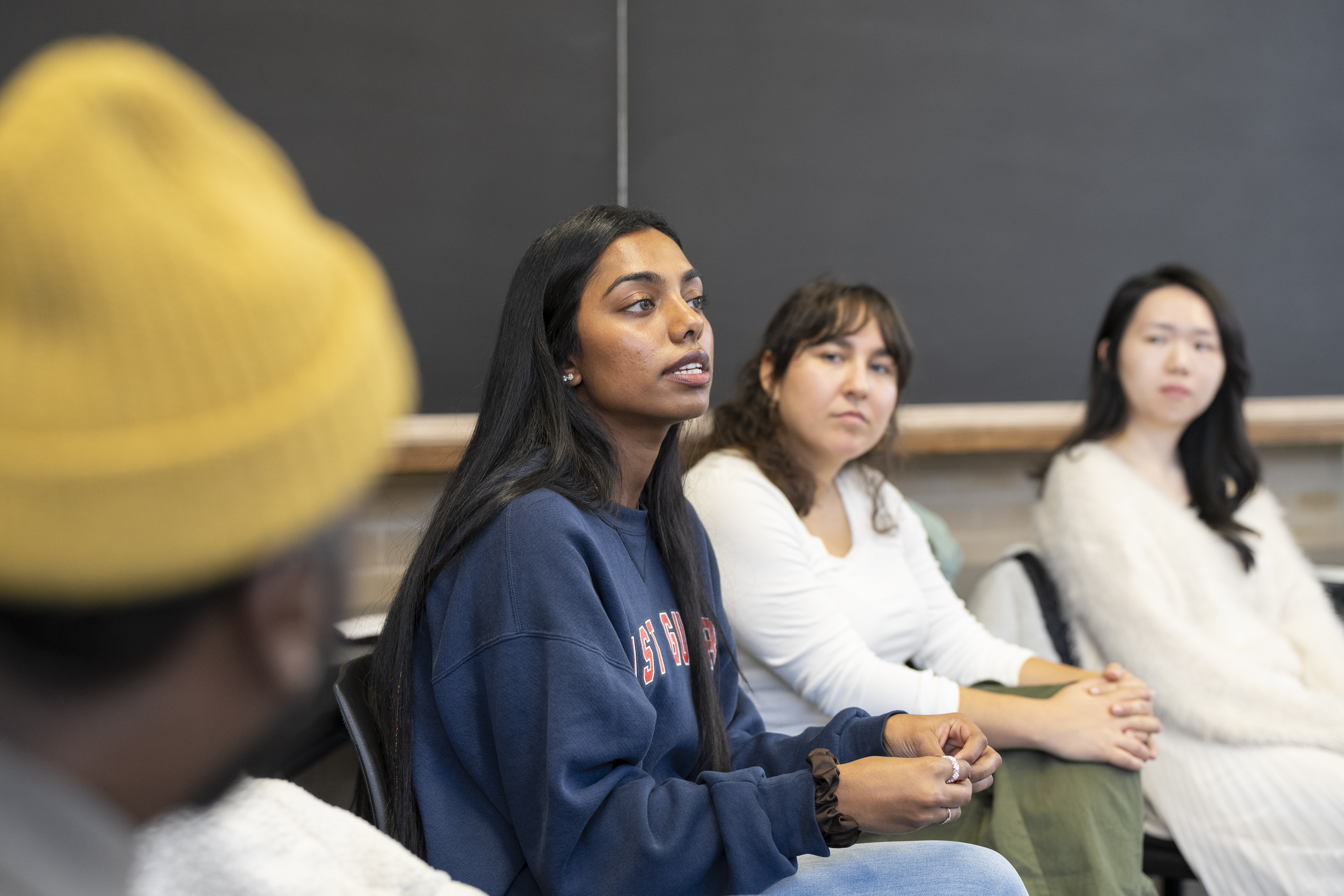 classroom image of three students looking a a woman in blue 