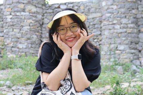 Woman sitting with head in hands with a yellow hat smiling