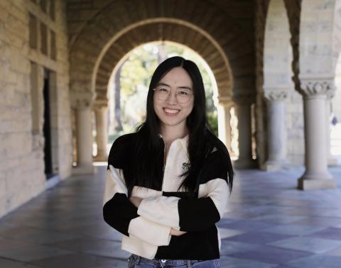 Woman in black and white sweater standing in a breezeway smiling