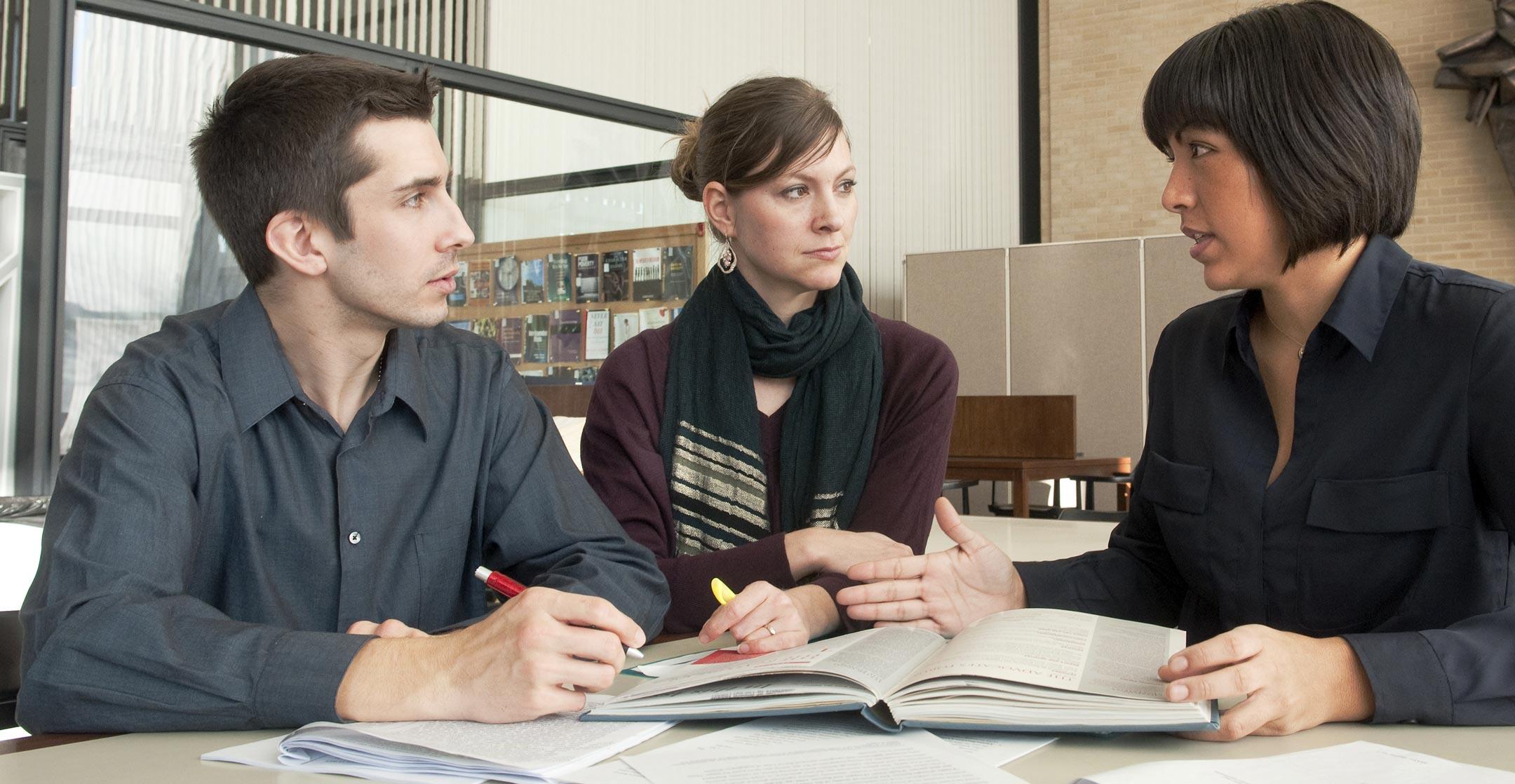 Three people talking with a book open between them