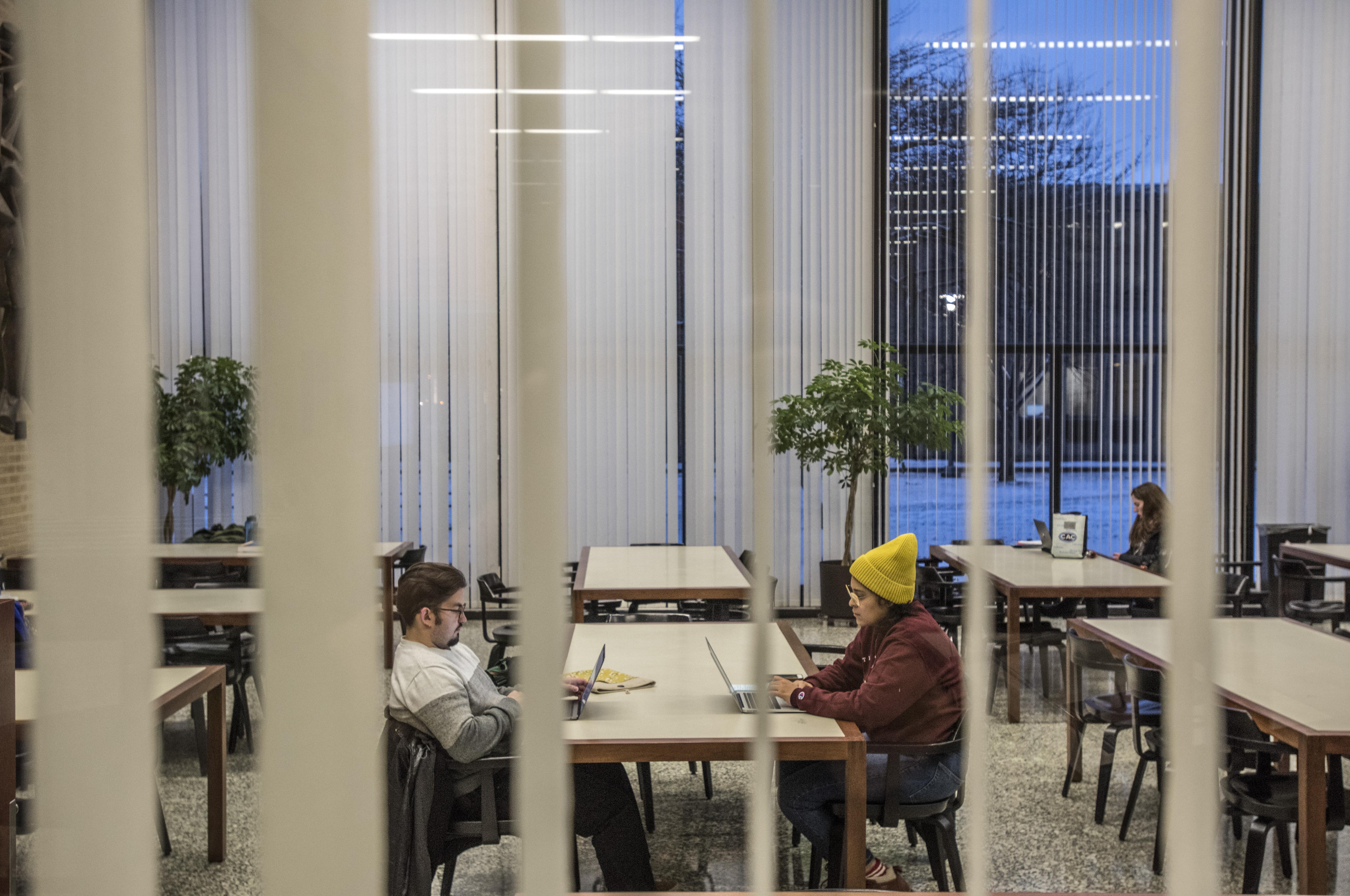 Students sitting in the library viewed through blinds