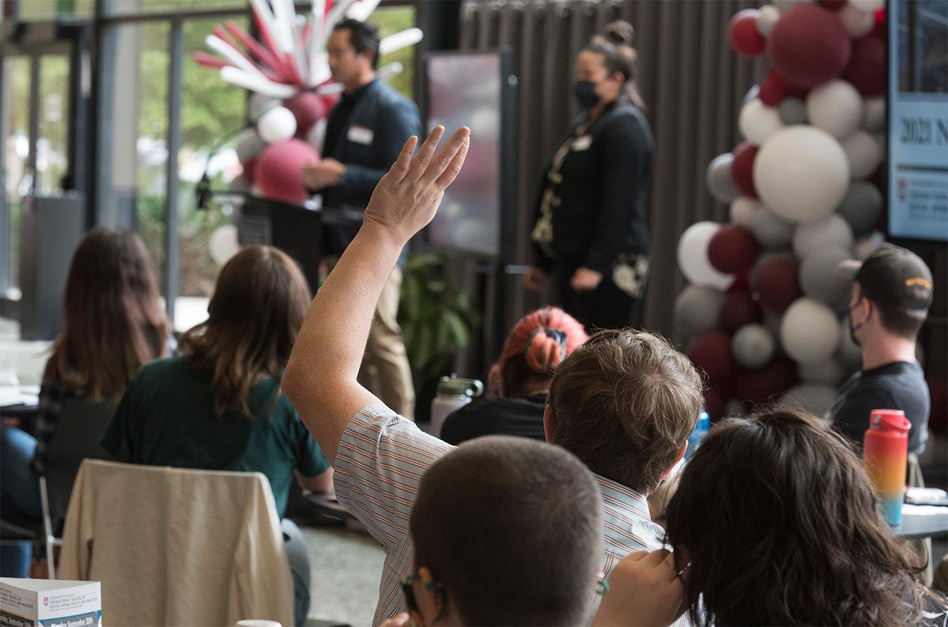 Master's Program students listening to a lecture with one student raising their hand