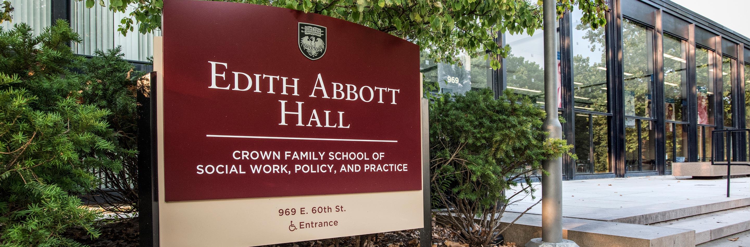 Front exterior view of Edith Abbott Hall from an angle. The maroon building sign for Edith Abbott Hall fills up the left side of the frame.