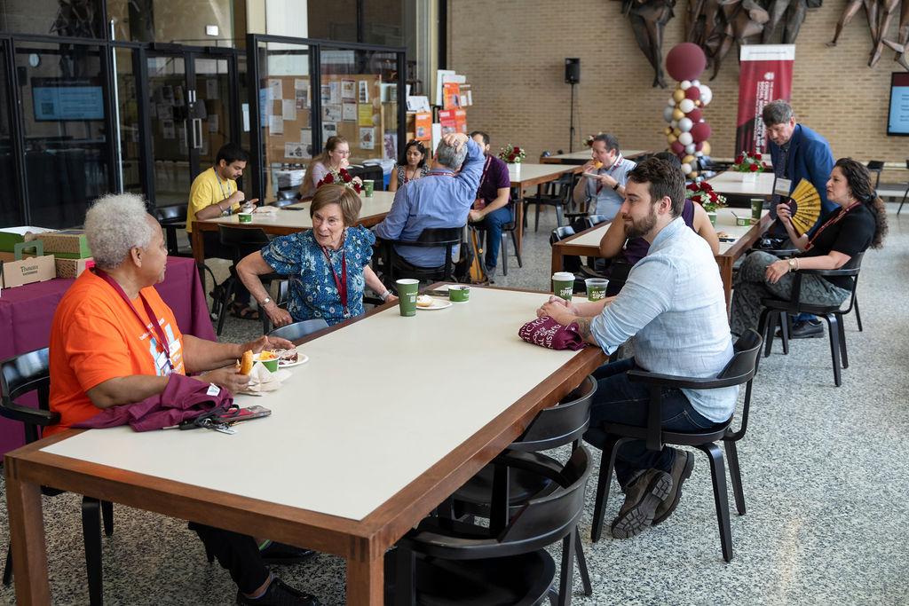 Group of people siting at tables chatting and eating 