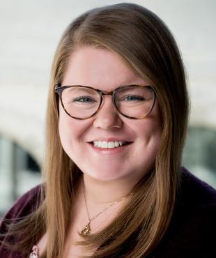 Woman in maroon with glasses smiling